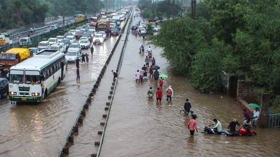 Commuters wade through waterlogged Delhi- Gurugram Expressway and service road after heavy rains at Narsinghpur in Gurugram, Monday, July 19, 2021. (PTI)