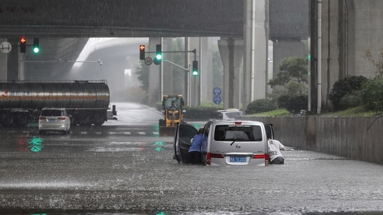 People push a van through flood waters along a street following heavy rains.(Photo by STR/AFP)