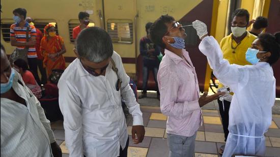 A BMC health worker collects swab samples for Covid-19 test of passengers arriving from outstation trains at Dadar station in Mumbai, earlier this month. (HT file)