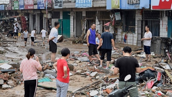 Residents converse on a muddy street after severe flooding and landslide in Henan province. (Photo by JADE GAO/AFP)