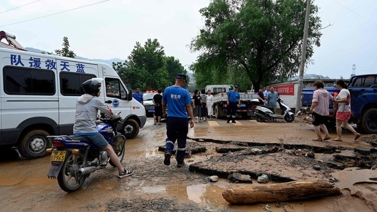Rescuers manage traffic on a muddy road after severe flooding and landslide in recent days have hit the county-level Gongyi city.(Photo by JADE GAO/AFP)