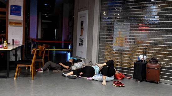 People rest on top of sacks in an arcade after their houses gets damaged by flood water. (Photo by JADE GAO/AFP)