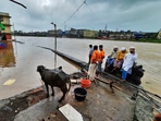 People look on from an elevated portion of an area submerged in flood waters, following heavy rain in Thane district on July 22. Heavy rains have been battering the coastal Konkan and parts of Western Maharashtra for the last two days.(PTI)