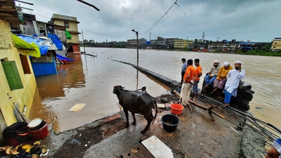 People look on from an elevated portion of an area submerged in flood waters, following heavy rain in Thane district on July 22. Heavy rains have been battering the coastal Konkan and parts of Western Maharashtra for the last two days. (PTI) People look on from an elevated portion of an area submerged in flood waters, following heavy rain in Thane district on July 22. Heavy rains have been battering the coastal Konkan and parts of Western Maharashtra for the last two days. (PTI)