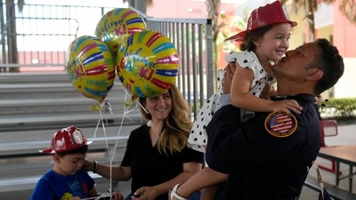 Members of Miami-Dade Fire Rescue's urban search and rescue team are reunited with their families after weeks of working on the rubble pile at the collapsed Champlain Towers South condominium. (AP)