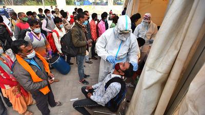 A health worker collects a swab sample from a passenger near Anand Vihar ISBT in New Delhi. (HT archive)