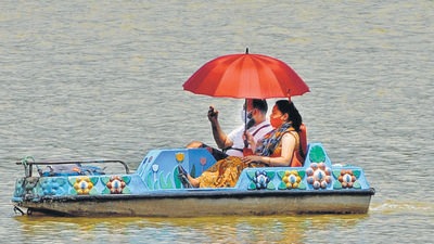 Deceived by clouds that made way for the sun, this couple turned to an umbrella to shield themselves while boating in Sukhna Lake, Chandigarh, on Saturday. (Ravi Kumar/HT)