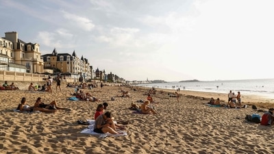 Tourists sunbathe on a beach by the sea in Saint-Malo, western France. (AFP)
