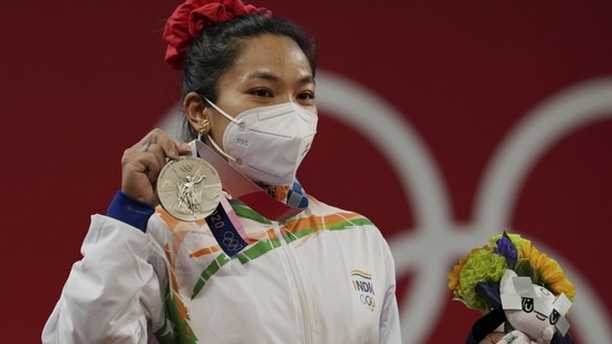 India's Mirabai Chanu wearing Olympic Rings ear-ring poses for photographs while standing on the podium after receiving the silver medal in women's 49 kg category weightlifting event at the Summer Olympics 2020, in Tokyo, Saturday, July 24, 2021.(PTI)