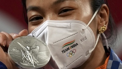 Tokyo Olympics 2020: India's Mirabai Chanu, wearing golden Olympic Rings ear-ring, poses for photographs while standing on the podium after receiving the silver medal in women's 49 kg category weightlifting event at the Summer Olympics 2020, in Tokyo. (PTI) Tokyo Olympics 2020: India's Mirabai Chanu, wearing golden Olympic Rings ear-ring, poses for photographs while standing on the podium after receiving the silver medal in women's 49 kg category weightlifting event at the Summer Olympics 2020, in Tokyo. (PTI)