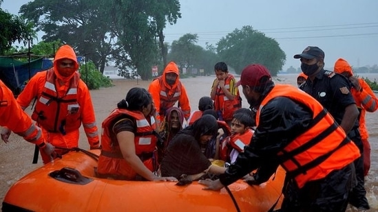 Rescue workers evacuate people from a flooded area to safer places after heavy rains in Kolhapur in the western state of Maharashtra on July 23.(REUTERS/Abhijeet Gurjar)
