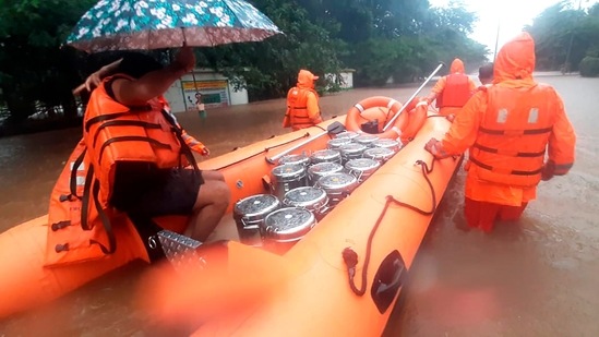 NDRF personnel carry food boxes for residents in Chiplun area in the western Indian state of Maharashtra on July 23, 2021. (AP)