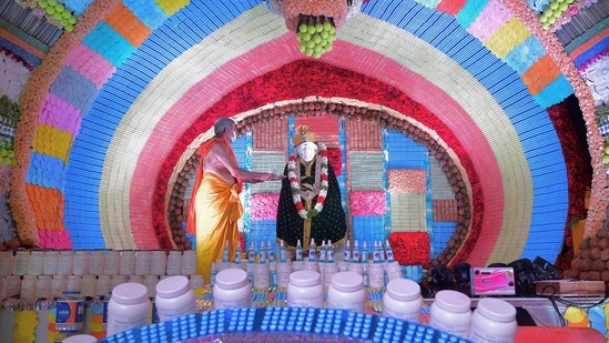 Seorang pendeta terlihat memberikan persembahan kepada berhala Bhagwan Sai Baba di dalam Kuil Sai Baba di Bangalore. Kuil itu dihiasi dengan obat-obatan, masker wajah, dan barang-barang lain yang digunakan untuk mencegah penyebaran Covid-19. (Manjunath Kiran/AFP)