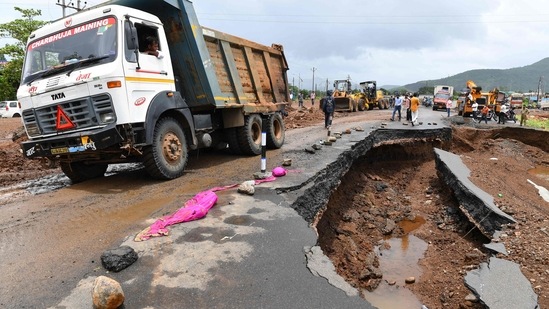 People gather along a road partially washed away from the rain at Mahad on July 24. (INDRANIL MUKHERJEE/AFP)