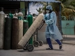 A hospital employee wearing protective gear as a precaution against the spread of the new coronavirus, transports oxygen tanks.(AP) A hospital employee wearing protective gear as a precaution against the spread of the new coronavirus, transports oxygen tanks.(AP)