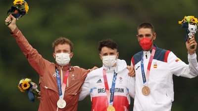 Tokyo 2020 Olympics - Mountain Bike - Men's Cross Country - Medal Ceremony - Izu MTB Course - Shizuoka, Japan - July 26, 2021.  Gold medallist Tom Pidcock of Britain celebrates on the podium with silver medallist, Mathias Fluckiger of Switzerland and bronze medallist, David Valero of Spain. REUTERS/Christian Hartmann (REUTERS)