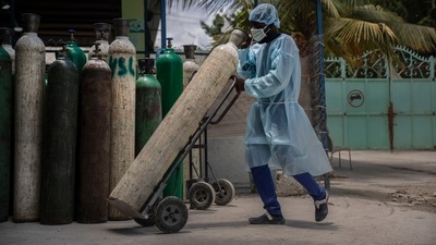 A hospital employee wearing protective gear as a precaution against the spread of the new coronavirus, transports oxygen tanks. (AP) A hospital employee wearing protective gear as a precaution against the spread of the new coronavirus, transports oxygen tanks. (AP)