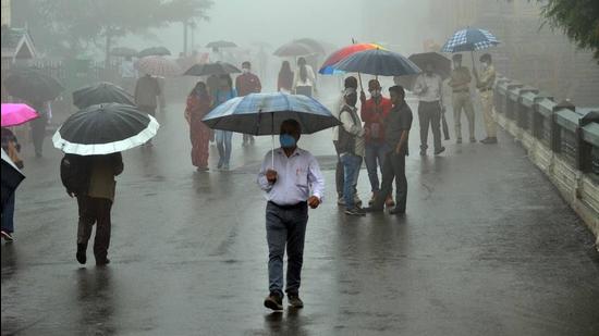 People walk amid light showers on The Ridge in Shimla on Monday. (Deepak Sansta/HT)