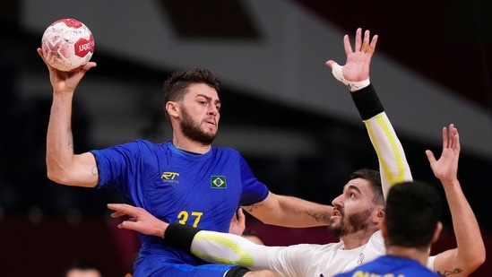 Brazil's Haniel Langaro, left, throws the ball as France's Ludovic Fabregas, second from right, tries to block during the men's Preliminary Round Group A handball match between Brazil and France at the 2020 Summer Olympics, Monday, July 26, 2021, in Tokyo, Japan. (AP Photo/Pavel Golovkin)(AP)