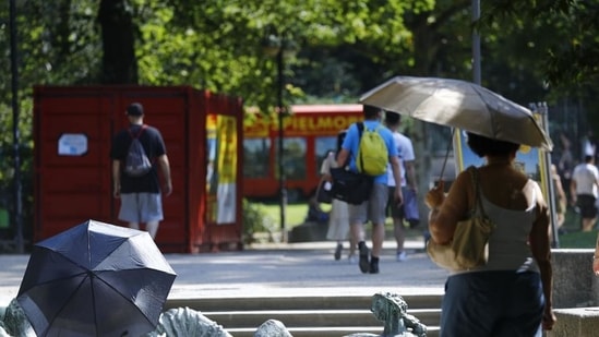 Pedestrians shelter from the sun under umbrellas during a heatwave in Frankfurt, Germany.(Bloomberg)