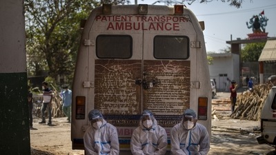 Exhausted workers, who bring dead bodies for cremation, sit on the rear step of an ambulance inside a crematorium, in New Delhi on April 24 (AP)