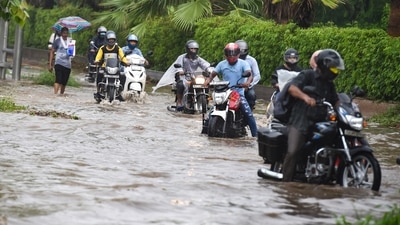Commuters wade through a waterlogged Ring Road on Tuesday morning. The city had experienced sultry weather on Sunday with some parts getting light rain. (PTI) Commuters wade through a waterlogged Ring Road on Tuesday morning. The city had experienced sultry weather on Sunday with some parts getting light rain. (PTI)