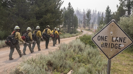Firefighters from New Mexico walk toward the Northwest edge of the Bootleg Fire while working to build a containment line on July 23 near Paisley, Oregon. It could be days before officials will be able to assess the damage done by the Dixie fire, California's largest and only one among dozens of blazes scorching lands across the US West.(Nathan Howard / AP)