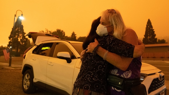 Evacuated residents hug near State Route 89 during the Dixie Fire in Greenville, California on July 24. Fires have already ravaged three times more vegetation this year than they had at this time in 2020, the worst fire year in California's history.(David Odisho / Bloomberg)
