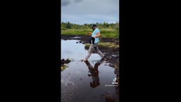 The image shows the man trying to cross a puddle.