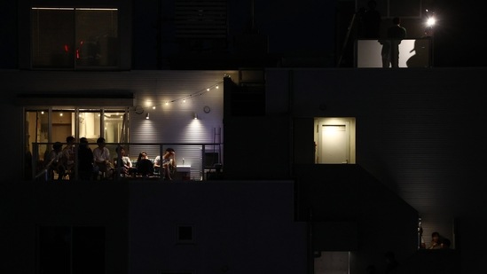 Residents watch a telecast of the opening ceremony of the Olympic Games as some look towards the stadium in Tokyo on July 23.(Edgar Su / REUTERS)