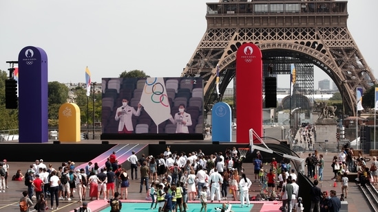 People watch the Tokyo 2020 Olympic Games opening ceremony being displayed on a screen at the Trocadero Gardens, next to the Eiffel Tower, in Paris on July 23.(Benoit Tessier / REUTERS)