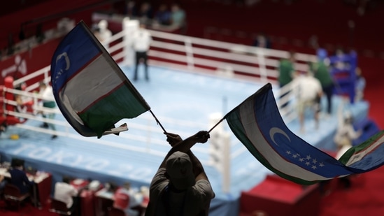 A spectator waves Uzbekistan flags during a fight between Mirazizbek Mirzakhalilov of Uzbekistan and Kurt Walker of Ireland, at Kokugikan Arena, in Tokyo, on July 28. Back at venues across Tokyo, national delegations have brought the noise, replacing fans kept out by coronavirus countermeasures.(Ueslei Marcelino / REUTERS)