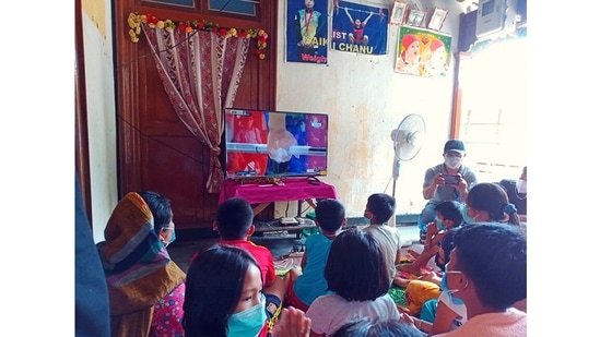 Family members and neighbours of Saikhom Mirabai Chanu gather to watch her lift in women's weightlifting 49kg category at Tokyo 2020 Olympics, on July 24. Images shared on social media have showed crowds, large and small, coming together around the world to celebrate Olympians.(PTI)