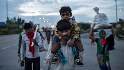 A migrant worker carries his son as they walk along a road with others to return to their village, during the first nationwide lockdown to limit the spreading of coronavirus disease (Covid-19), in March last year, New Delhi. (REUTERS File) A migrant worker carries his son as they walk along a road with others to return to their village, during the first nationwide lockdown to limit the spreading of coronavirus disease (Covid-19), in March last year, New Delhi. (REUTERS File)