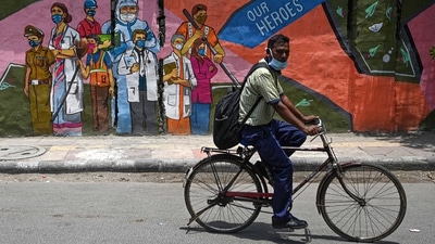 A cyclist passes by a wall mural depicting frontline Covid-19 coronavirus workers, in New Delhi. (Money Sharma / AFP) A cyclist passes by a wall mural depicting frontline Covid-19 coronavirus workers, in New Delhi. (Money Sharma / AFP)