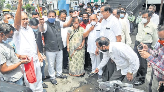 Congress party workers gather around a pothole on Tilak road on Wednesday, to stage a protest regarding the poor state of roads in the city. (HT PHOTO)