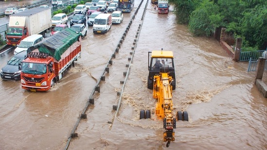 Commuters wade through the waterlogged Delhi- Gurugram Expressway and service road after heavy rains at Narsinghpur, in Gurugram on July 28. The lanes of the Delhi-Gurgaon Expressway were flooded, yet again, on a day that also marked the fifth anniversary of the infamous “Gurujam” incident of 2016 when commuters were stuck on the expressway for nearly two days due to rains.(PTI)