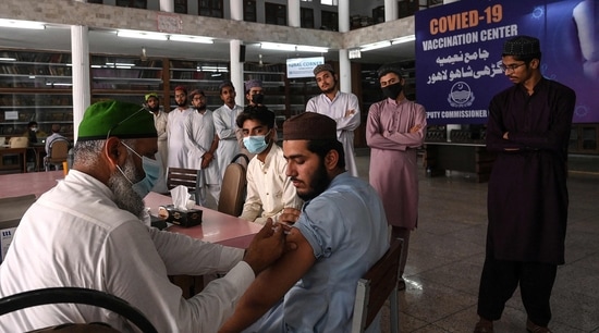 A health worker inoculates a student with a dose of the CanSino Biologics' Covid-19 coronavirus vaccine at Jamia Naeemia seminary in Lahore. (AFP)