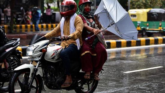 A pillion rider on a bike tries to hold an umbrella to protect herself from rainfall, in New Delhi on Wednesday, July 28. (ANI)
