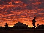 A jogger runs past the Sydney Opera House at dawn in Sydney, Wednesday, July 28, 2021. Australia’s largest city Sydney will remain in lockdown for another four weeks due to a growing Covid-19 cluster. (Mick Tsikas/AAP Image via AP)