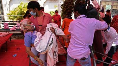 A family member carries a patient breathing with the help of oxygen being provided by a gurdwara, under a tent installed along the roadside in Ghaziabad on May 4. (AFP) A family member carries a patient breathing with the help of oxygen being provided by a gurdwara, under a tent installed along the roadside in Ghaziabad on May 4. (AFP)