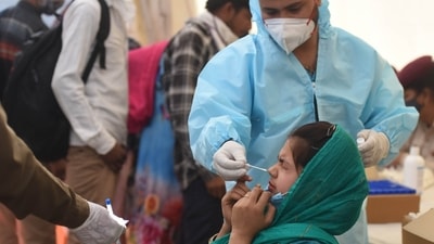 A health worker collects a swab sample for Covid-19 testing at Anand Vihar Bus Terminal, in New Delhi. (Raj K Raj/HT file photo)