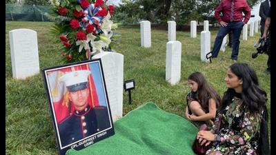Manpreet Kaur sits on a mat at the grave of her brother Cpl Gurpreet Singh, at Arlington National Cemetery, accompanied by Singh’s niece. Singh served in the US Marine Corps and was killed in Afghanistan in 2011. He is only the second Sikh soldier to be buried in the cemetery. (Photo courtesy: Sikh American Veterans Alliance)