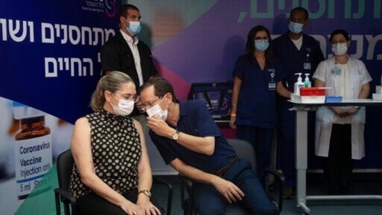 Israeli President Isaac Herzog speaks to his wife, Michal, left, before the couple received a third coronavirus vaccine at the Sheba Medical Center in Ramat Gan.(AP)