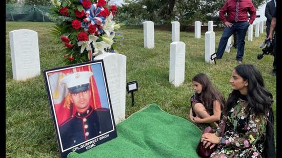 Manpreet Kaur sits on a mat at the grave of her brother Cpl Gurpreet Singh, at Arlington National Cemetery, accompanied by Singh’s niece. Singh served in the US Marine Corps and was killed in Afghanistan in 2011. He is only the second Sikh soldier to be buried in the cemetery. (Photo courtesy: Sikh American Veterans Alliance)