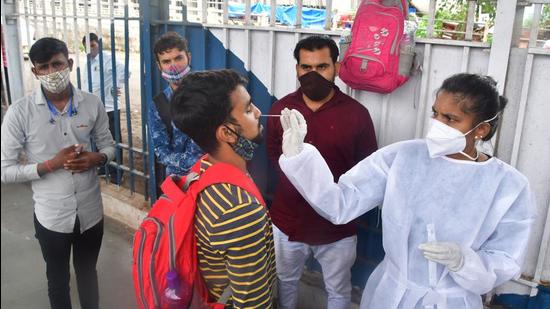 A BMC healthcare worker collects swab samples of passengers at Dadar station. (HT PHOTO)