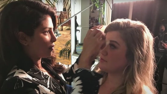 Priyanka Chopra fixing Kelly Clarkson's makeup backstage at an event.