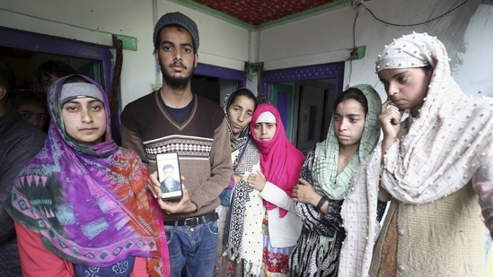Family members of Gulab Nabi, who died in the flash floods, share a picture of the victim with the media.(PTI)