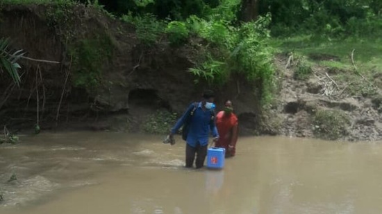 Health workers cross rivulet in Tripura to ensure Covid-19 vaccination to people living in remote villages.(HT Photo)