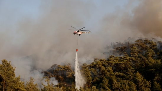 A firefighting helicopter drops water on a wildfire near Marmaris, Turkey on July 31, 2021. (REUTERS/Umit Bektas)